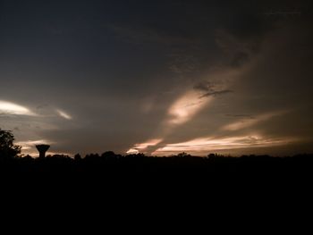 Silhouette trees on field against sky at sunset