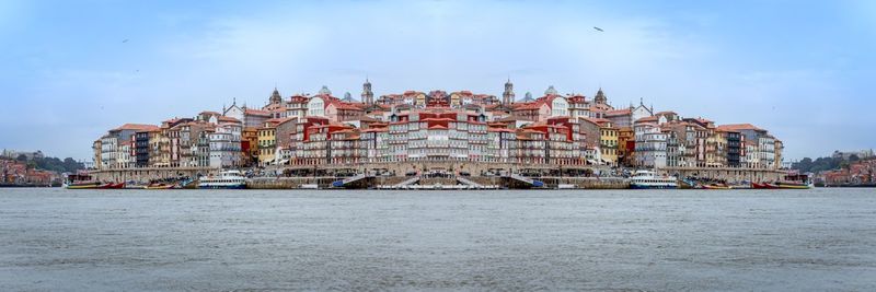 View of buildings and sea against cloudy sky