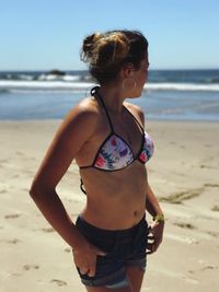 Young woman standing on beach against sky