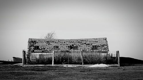 Abandoned built structure on field against clear sky