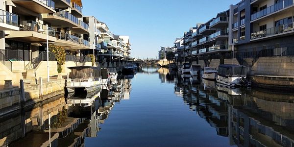 Canal amidst buildings in city against sky