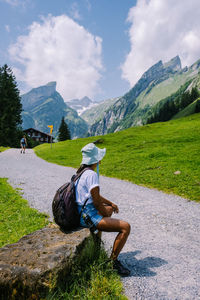 Man sitting on mountain against sky