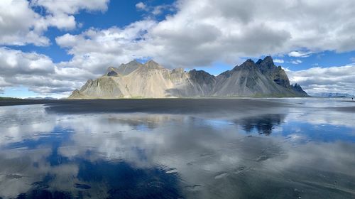 Scenic view of lake by snowcapped mountains against sky