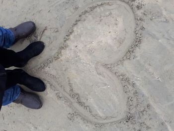 Low section of man standing on sand