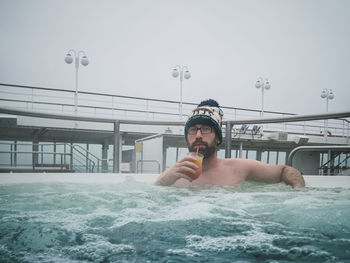 Portrait of shirtless man drinking juice in hot pool