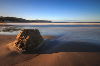 Scenic view of beach against clear blue sky