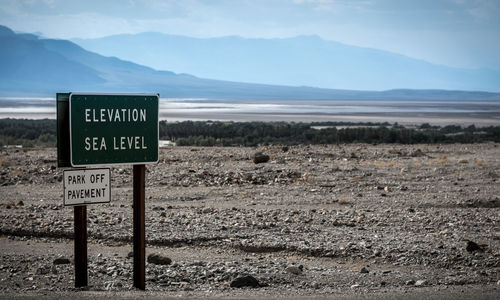 Information sign on field against sky