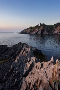 Scenic view of rocks in sea against clear sky