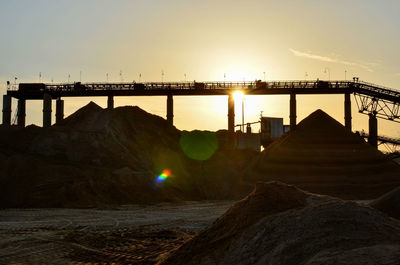 Bridge over land against sky during sunset