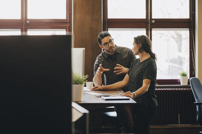 Mid adult businessman discussing new plan with female colleague in office