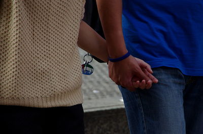 Midsection of couple holding hands while walking outdoors