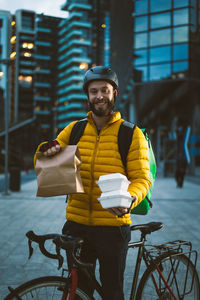 Young man with bicycle standing in city