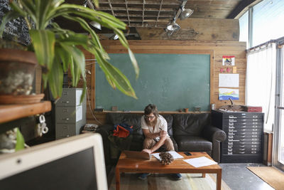 Rear view of woman sitting on table at home