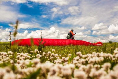 Man with flowers on field against sky