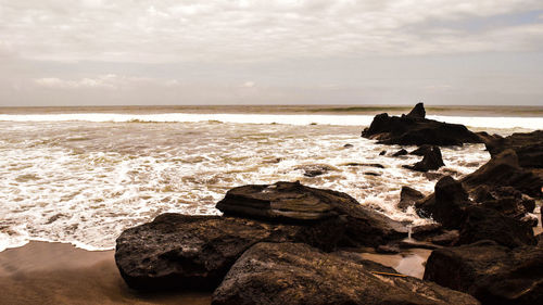 Rock formation on beach against sky