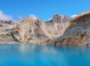 Scenic view of lake and mountains against blue sky