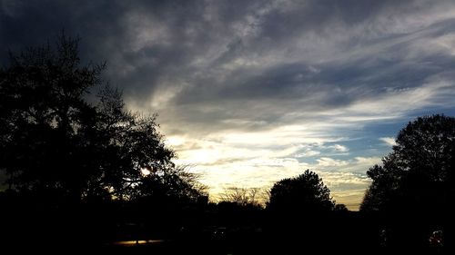 Silhouette of trees against cloudy sky