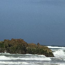 Scenic view of sea and rocks against clear sky