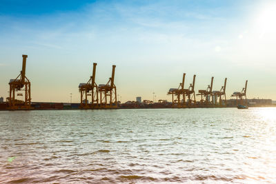 Cranes at commercial dock against sky