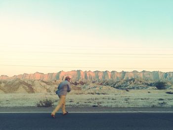 Full length of man walking by field on road