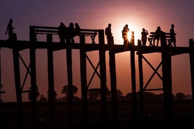 Low angle view of silhouette people on u bein bridge during sunset against sky