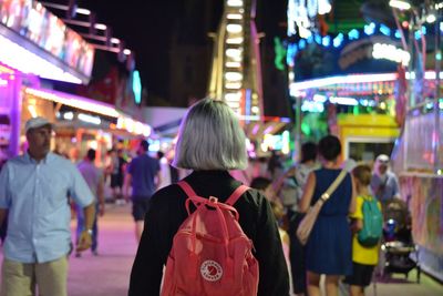 Rear view of people standing on street at night