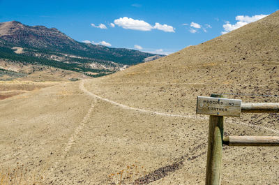 Warning sign on wooden fence against mountains