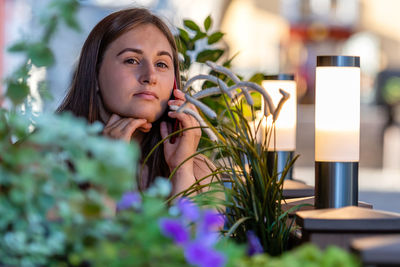 Young woman talking on phone sitting outdoors