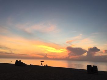 Scenic view of silhouette beach and sea against sky during sunset