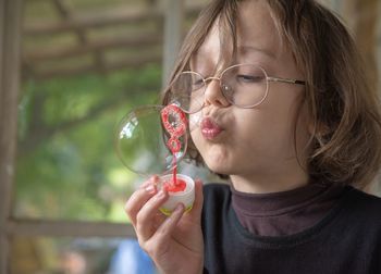 Close-up of boy blowing bubble at home