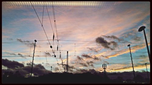 Low angle view of electricity pylon against cloudy sky