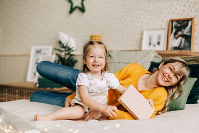 Mom and daughter read fairy tales in the bedroom on the bed on christmas or new year's eve. 
