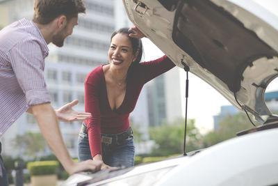 Young couple standing on car