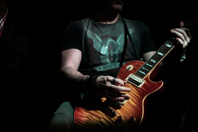 Midsection of man playing guitar