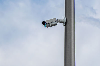 Low angle view of security camera against sky