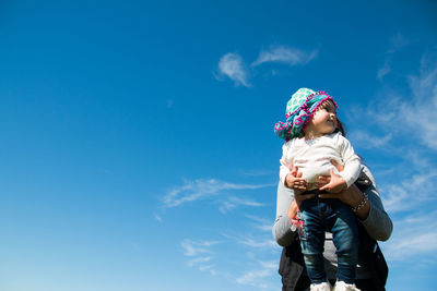 Mother holding babygirl sky background