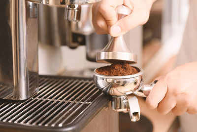 Close-up of hands holding coffee maker 