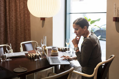 Businesswoman working on laptop in restaurant