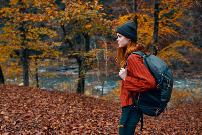 Full length of woman standing by tree during autumn