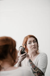 Young woman applying make-up at home