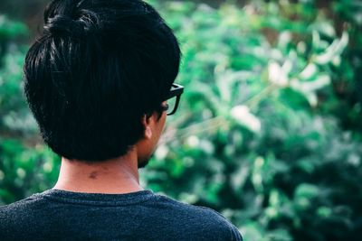 Rear view of young man standing against plants