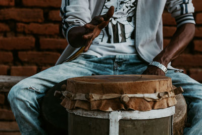 Midsection of man playing drums