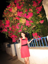 Portrait of young woman standing by flowering plants