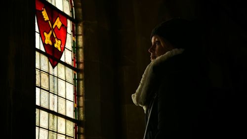 Side view of young woman looking away against emblem on window