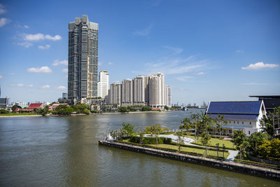 Buildings by river against sky