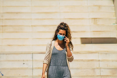 Portrait of young woman standing against wall