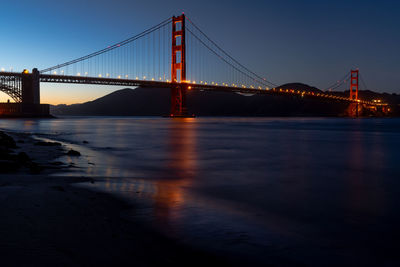 Low angle view of illuminated bridge over bay at night