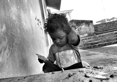 Close-up of boy crouching by wall