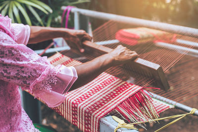 Midsection of woman weaving loom