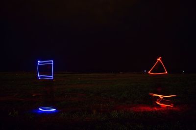 Light trails on field against sky at night